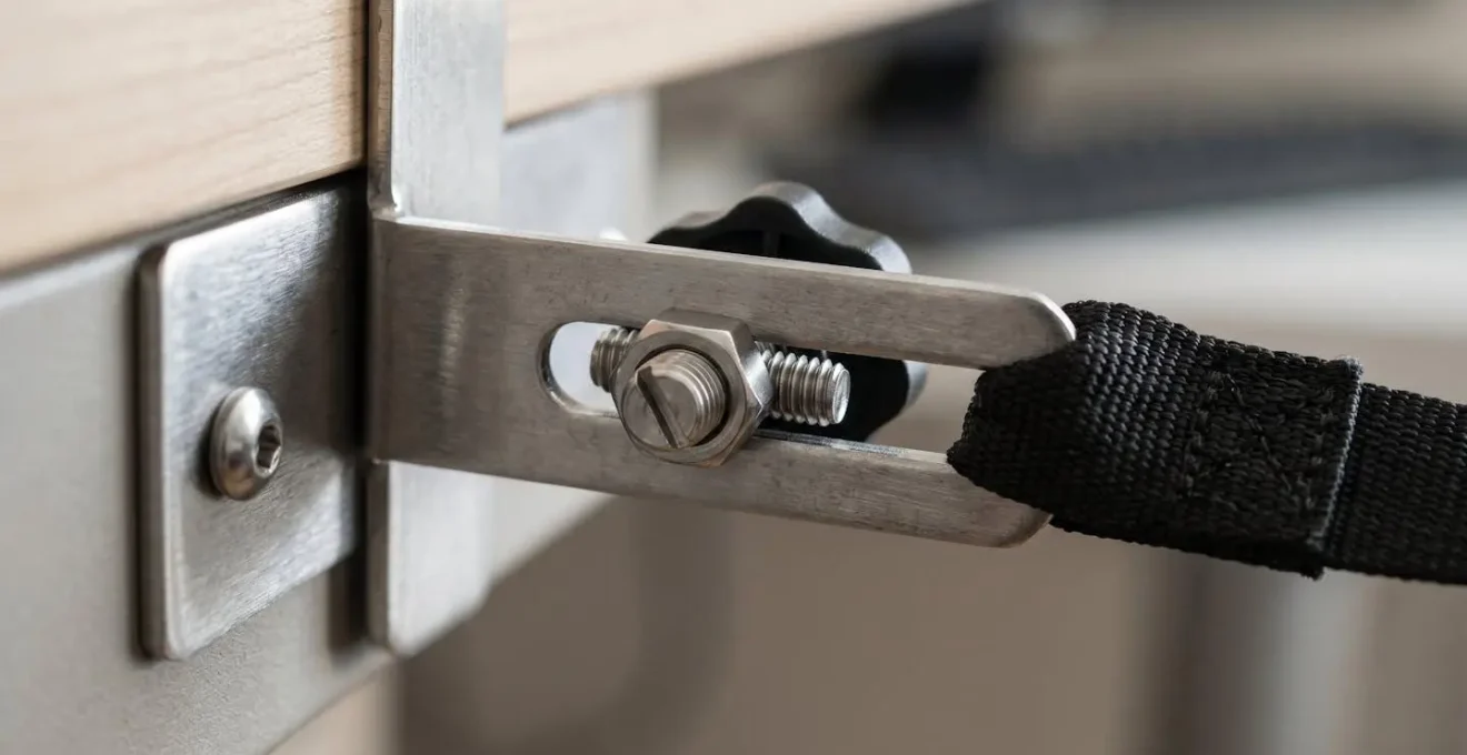 Détail macro d'un système de fixation anti-basculement pour meuble avec sangle tendue et ancrage métallique